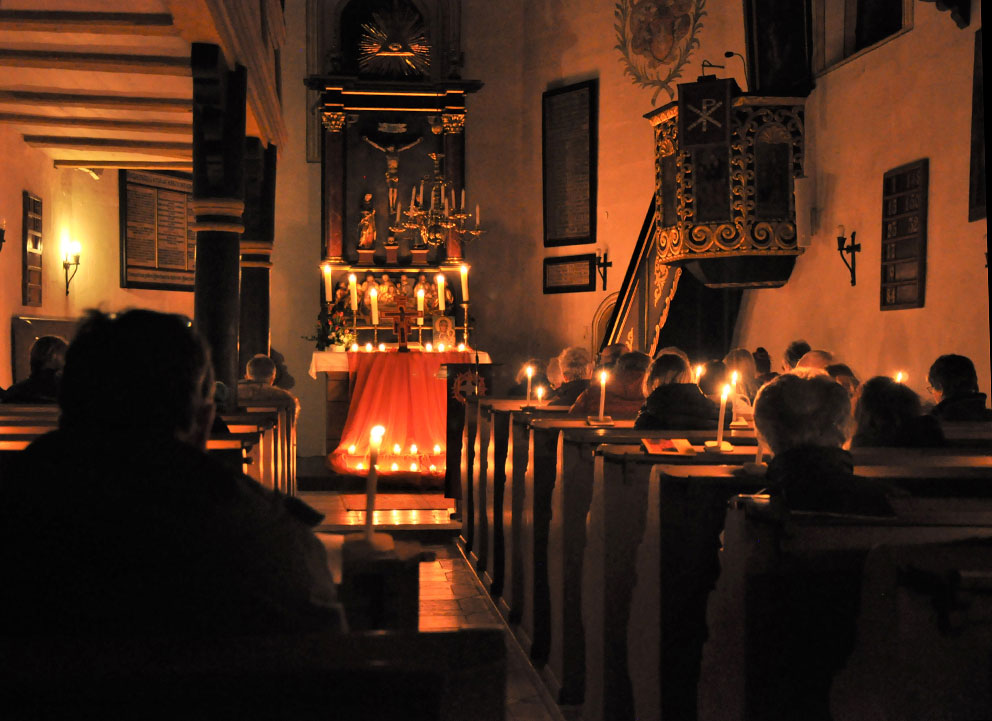 Innenaufnahme der St. Veitkirche Altenthann, von Kerzen beleuchtet.